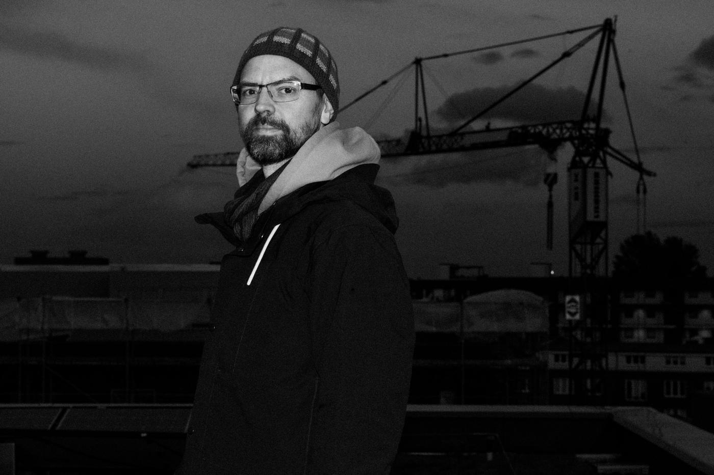 Tilo aka bassoContinuo on a rooftop at dusk, construction crane behind him